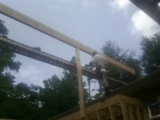 Carpenter setting a ridge beam over a new addition frame — Ice Dam Removal by Roofing Brothers in Creswell