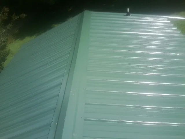 New green metal panels meeting at the ridge of a roof — Flat Roof Repair work by our crew in Creswell