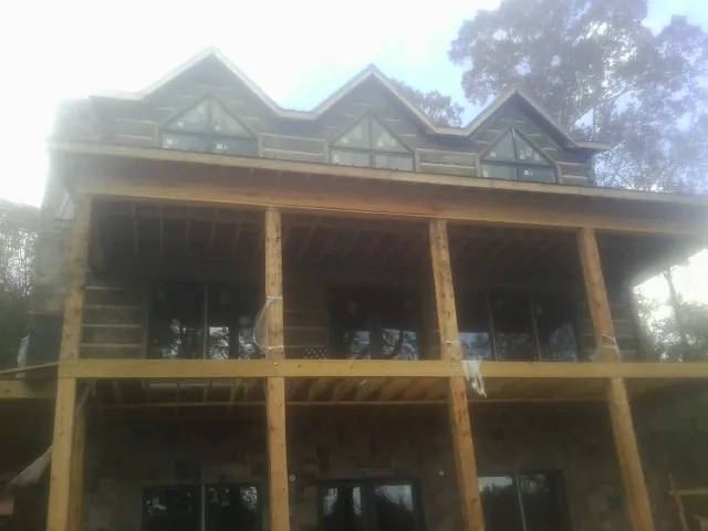 Dormers and porch framing on a large log home under construction — Roof Coating work by our crew in Creswell