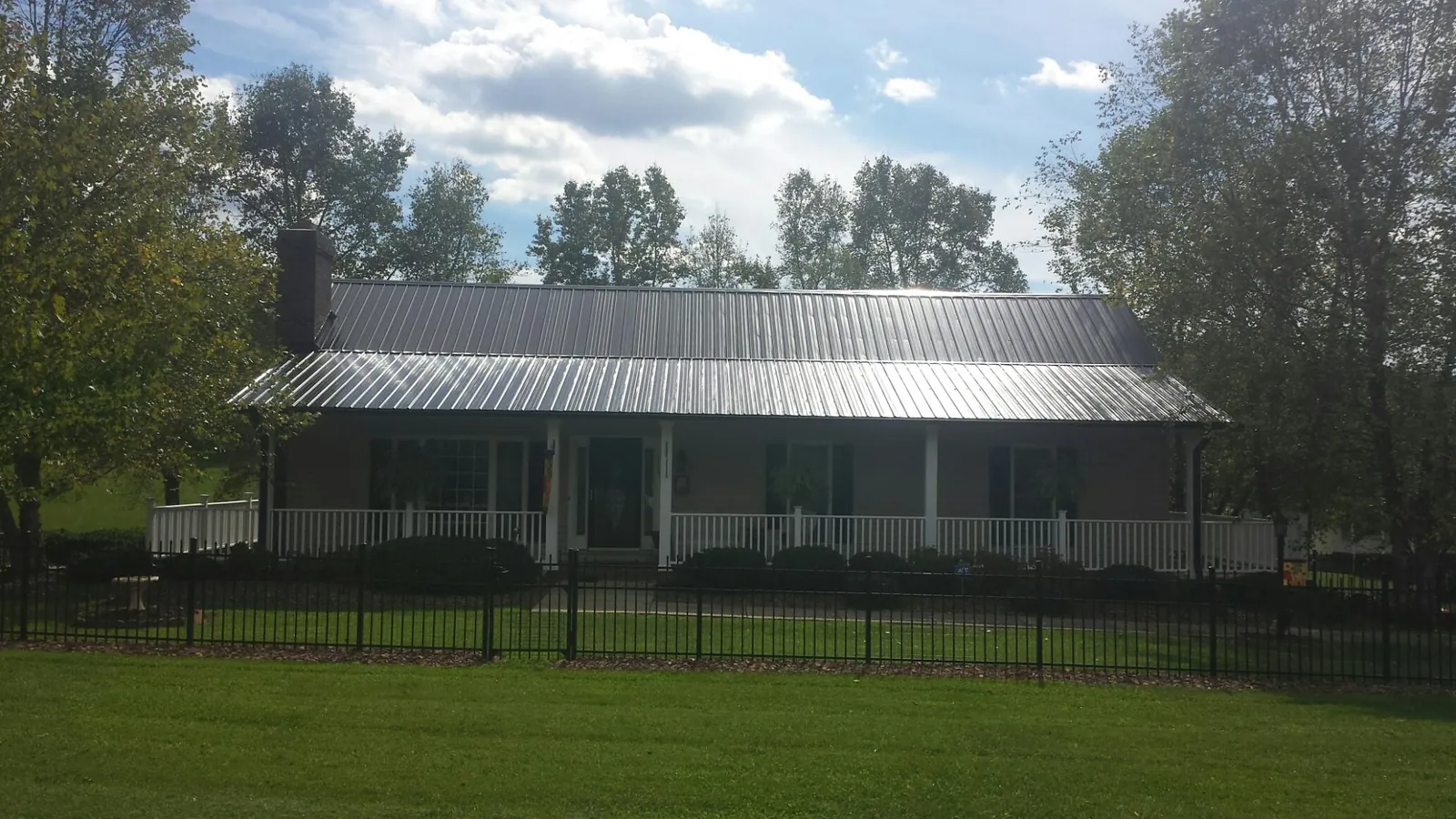 Gray metal roof on a brick ranch with a full width front porch — Gutter Guard Installation work by our crew in Creswell